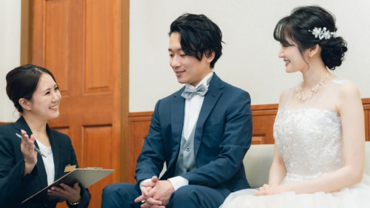 にこやかに新郎新婦と会話するウェディングプランナーの様子。