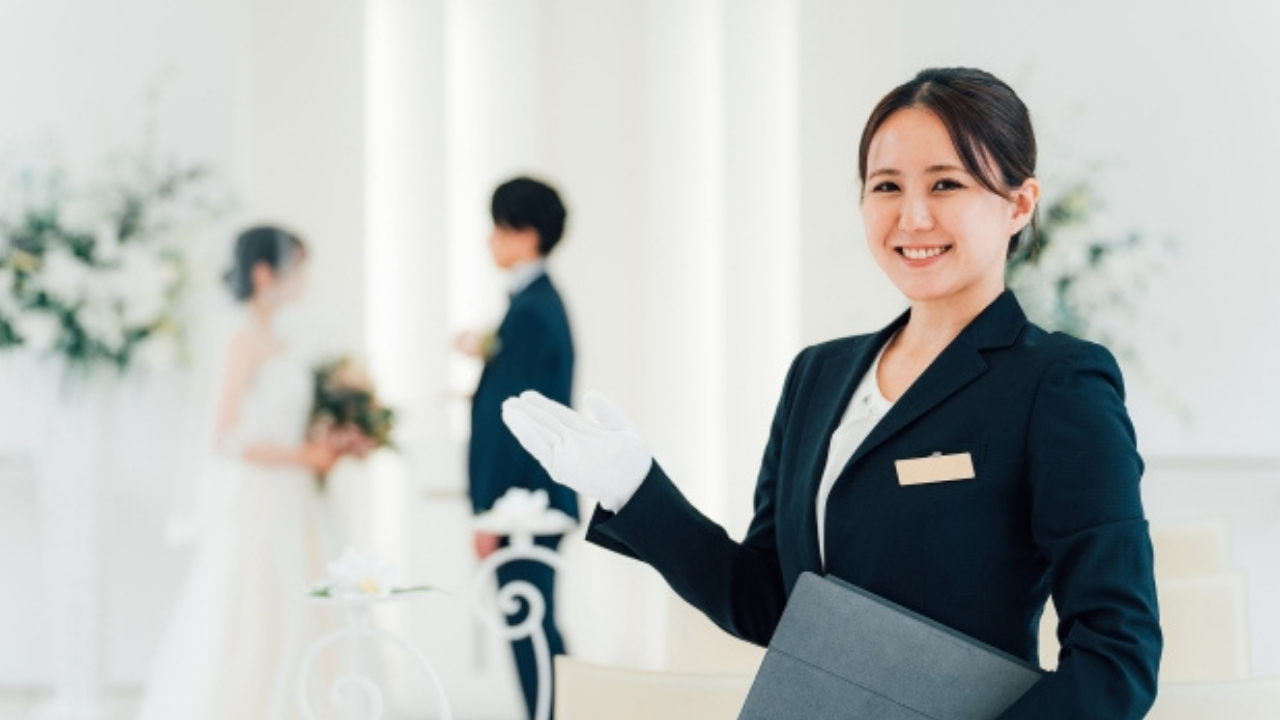 挙式の様子。手前には笑顔で立つウェディングプランナーの姿。