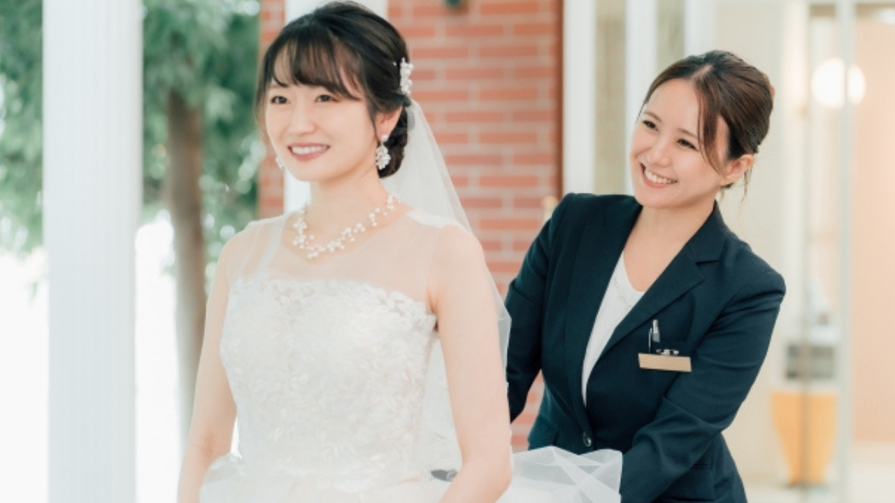 新婦のドレスを整えるブライダルスタッフの画像。