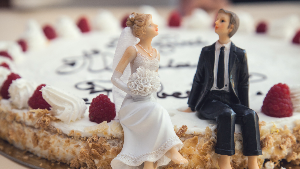 新郎新婦の形をしたシュガークラフトが乗ったウェディングケーキの画像。