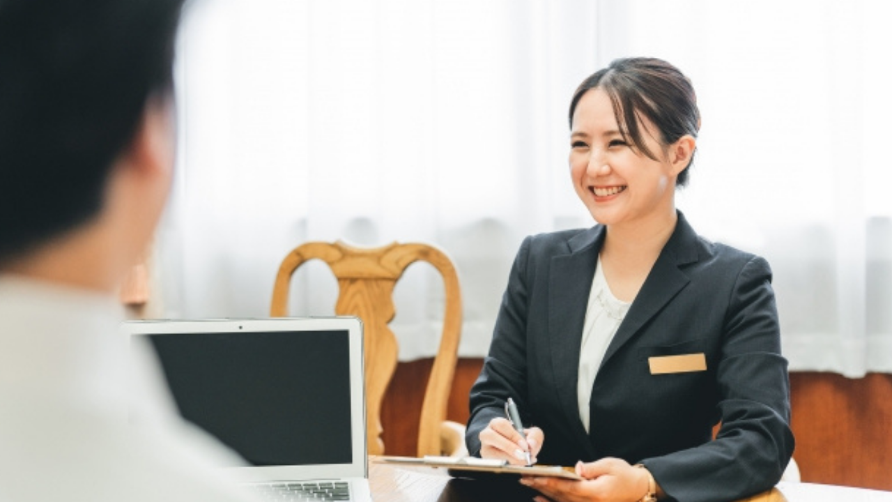 "笑顔で対応するウェディングプランナーの姿。コミュニケーション力が高い人物のイメージ。