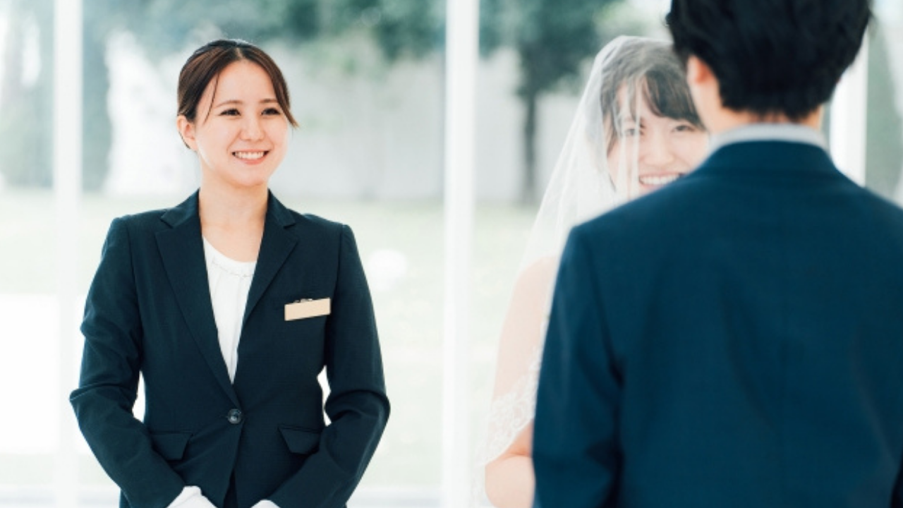 笑顔で新郎新婦を見守るウェディングプランナーの姿。